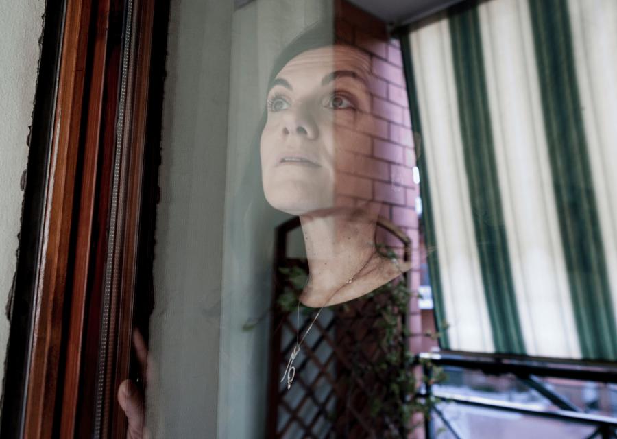Donna che guarda fuori dalla finestra in casa