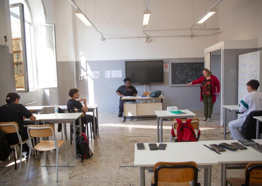classe scolastica, in primo piano un banco pieno di cellulari