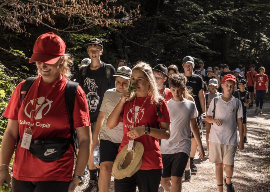due operatrici con dei bambini camminano in fila indiana nel bosco
