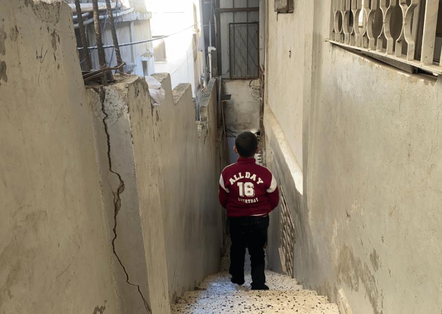 Bambino di spalle di fronte a scale di una casa in Cisgiordania