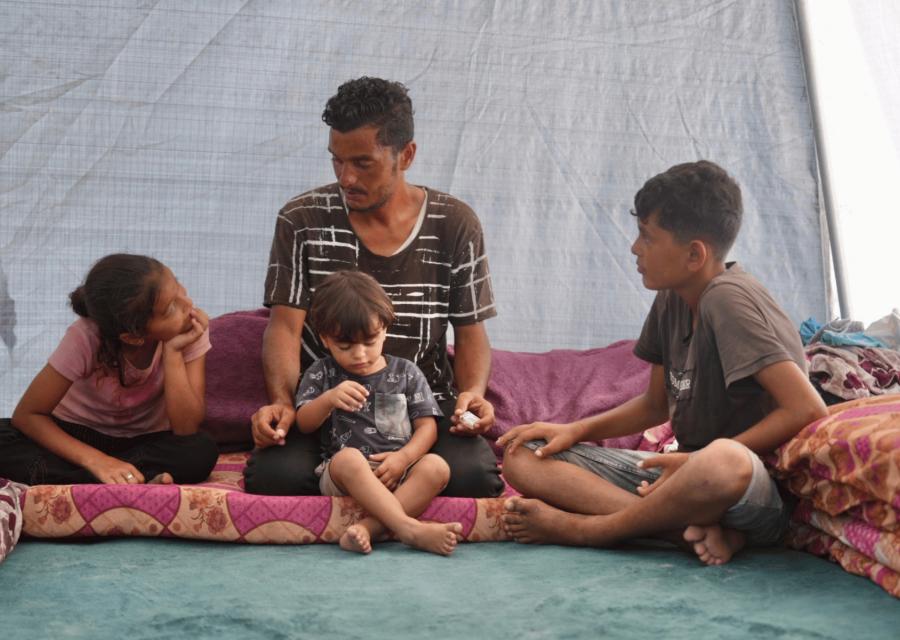 Genitore con 3 bambini seduti nella loro tenda 