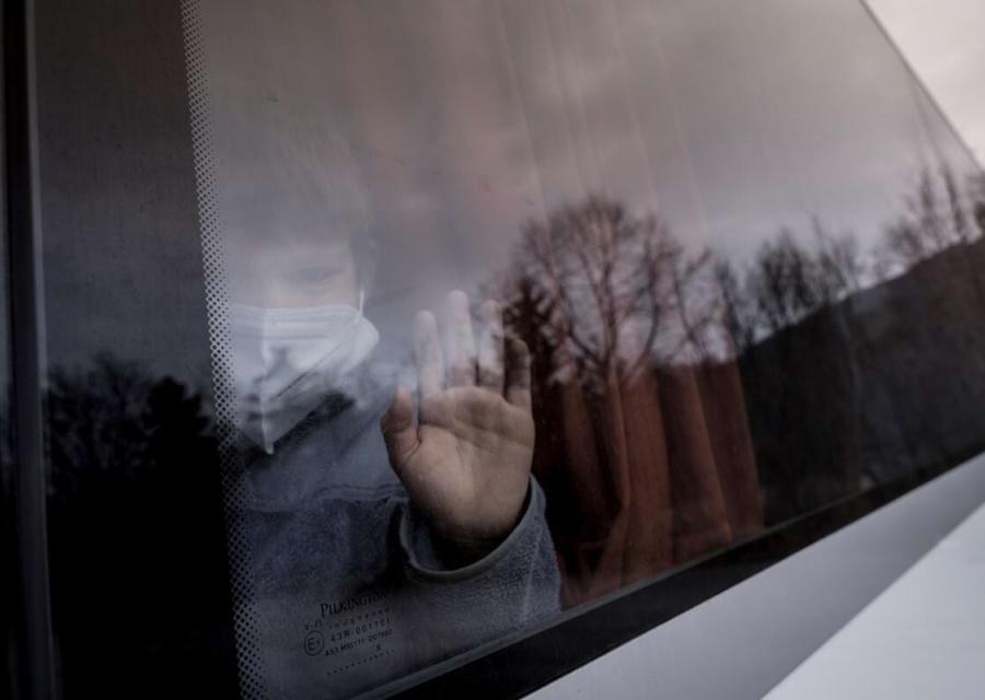 ritratto di un bambino dietro il finestrino di un pullman, con la mano addosso al vetro.