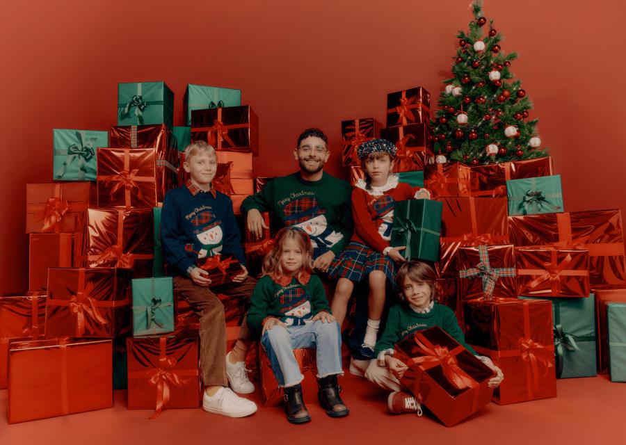 Rocco Hunt insieme a bambini e bambine con indosso il maglione natalizio del Christmas Jumper Day 2024