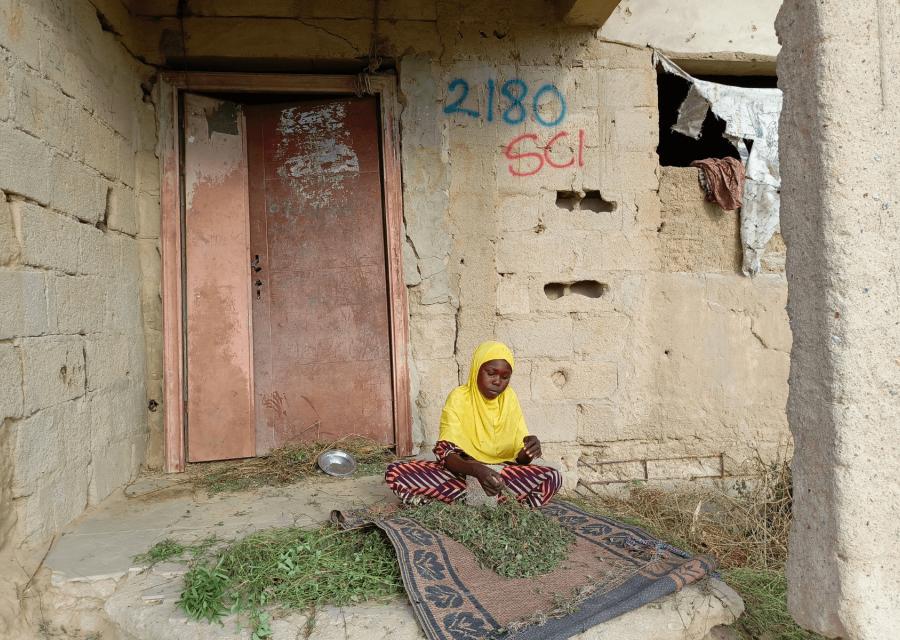 Bambina nigeriana seduta di fronte la porta di casa