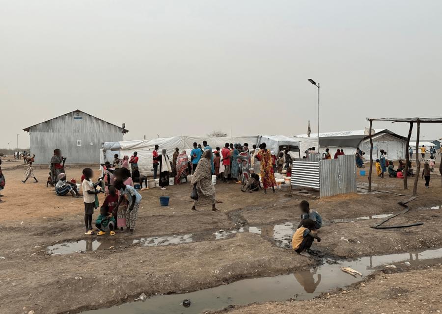 Stazione base per l'acqua in Sudan con adulti e bambini 