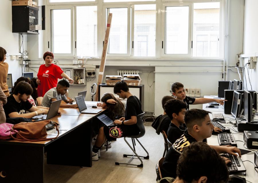 clase di ragazzi che lavorano al computer con gli operatori di Save the Children 