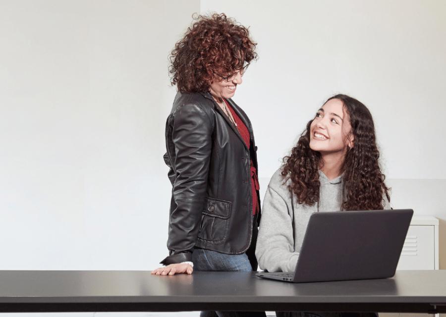 Ragazza con pc davanti che guarda un'adulta alla sua sinistra