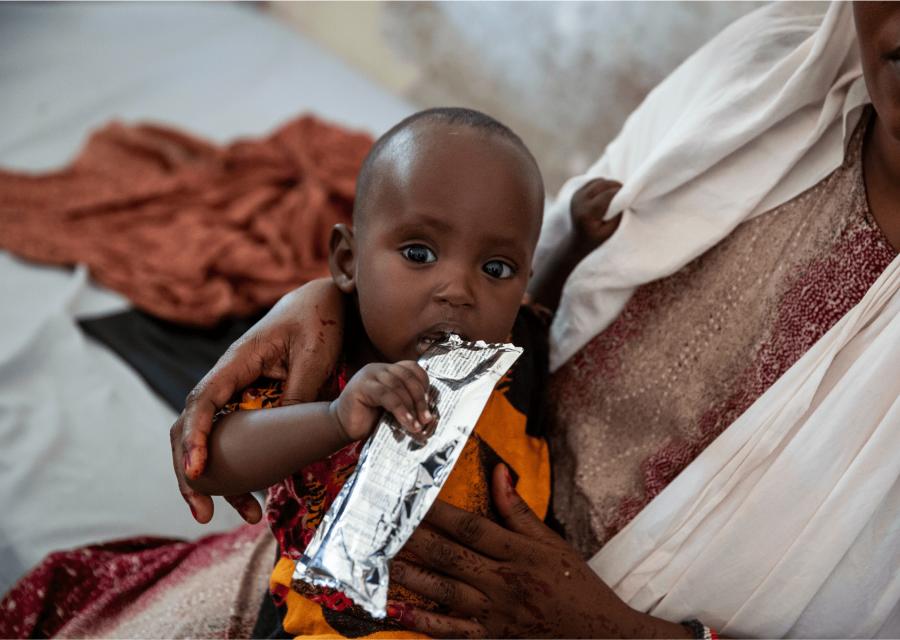 Bambino malnutrito mentre mangia una bustina di cibo per cura nutrizionale