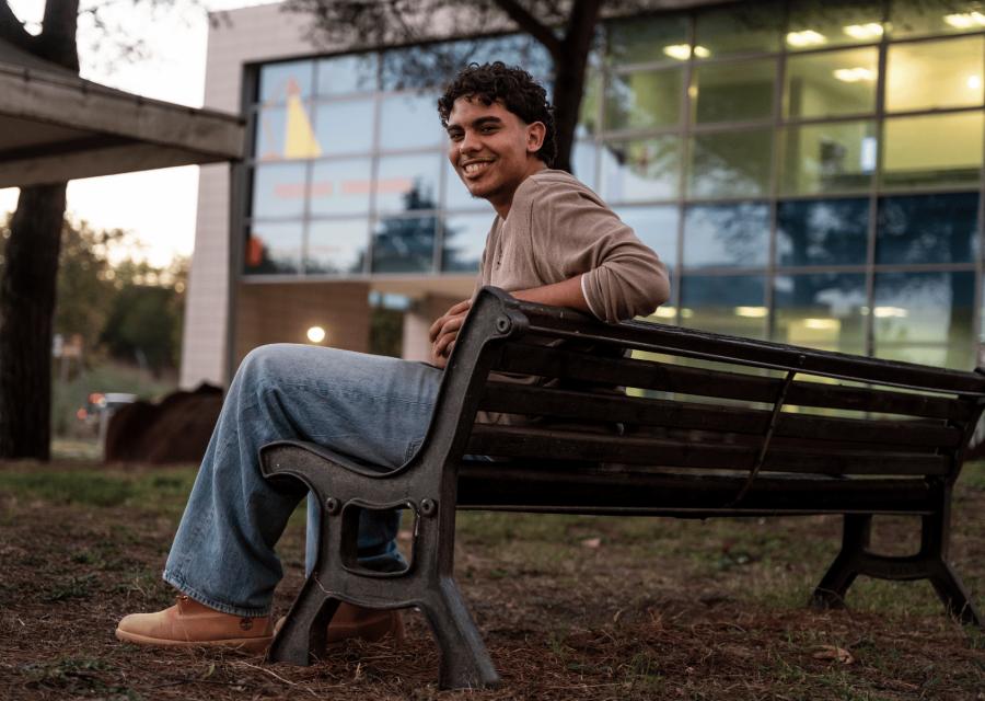 Ragazzo che sorride seduto su una panchina del Punto Luce
