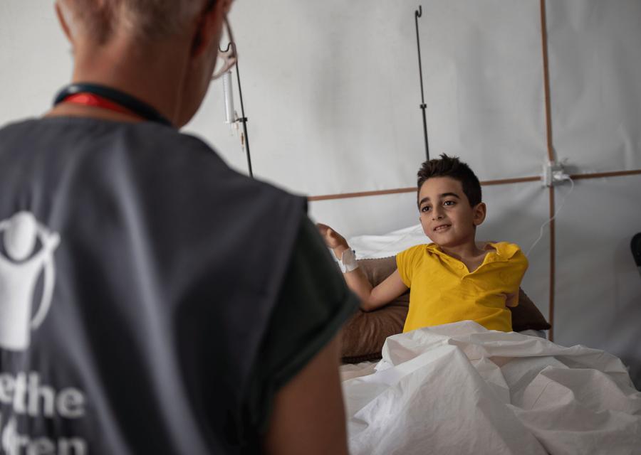 Operatrice Save the Children a Gaza di fronte a un bambino su letto di ospedale