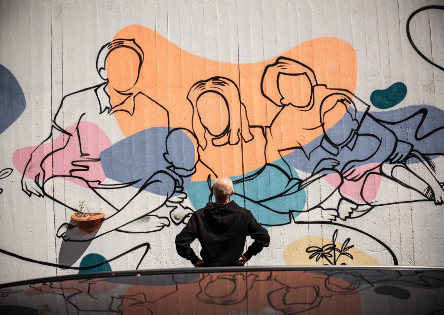 Uomo che guarda murales con famiglia disegnata