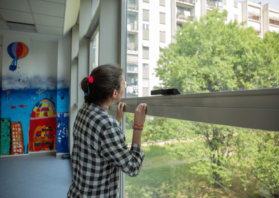 ragazza di fronte ad una finestra affacciata su spazio verde