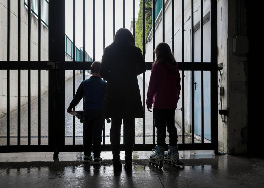 Mamma e bambini di spalle di fronte a un cancello 
