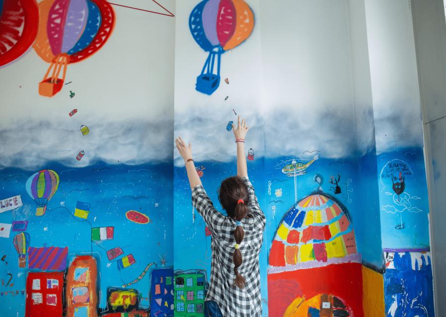 Ragazza di spalle di fronte a murales colorato 