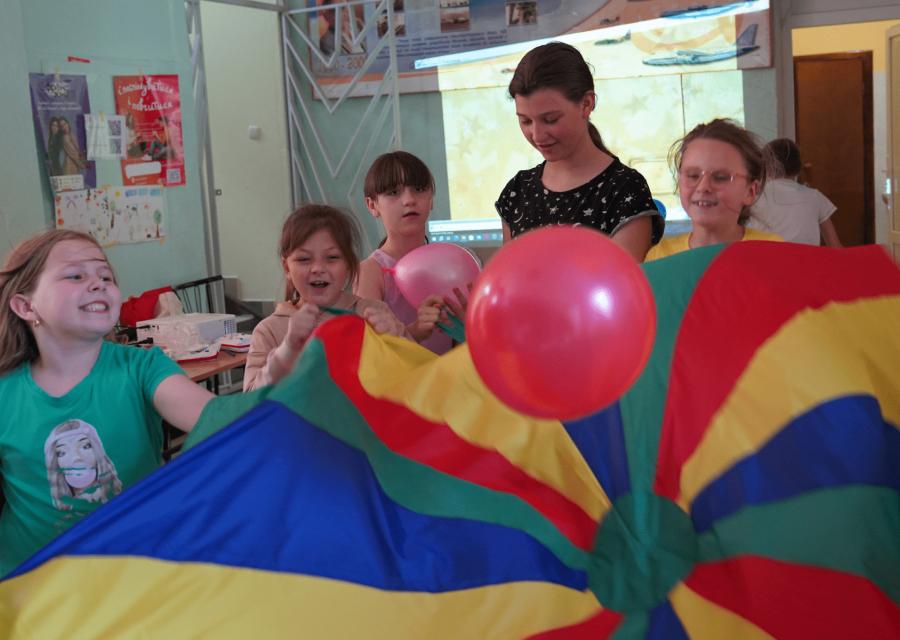 bambini e bambine con una bandiera colorata che giocano sorridenti 