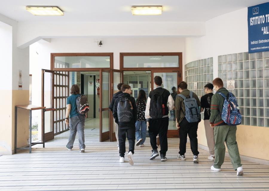 Studenti con zaino di scuola che camminano verso la porta di entrata di scuola.