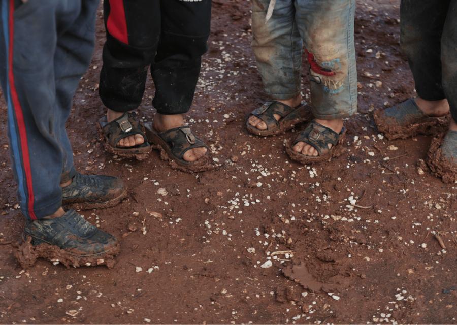 Piedi di bambini tra il fango 