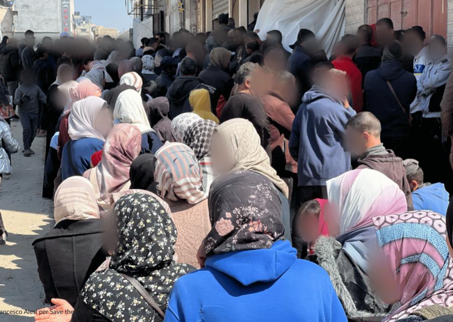 Persone di spalle in fila  per ricevere gli aiuti umanitari a Gaza