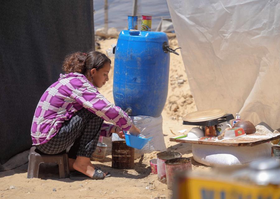 Bambina a Gaza davanti alla tenda con pentole