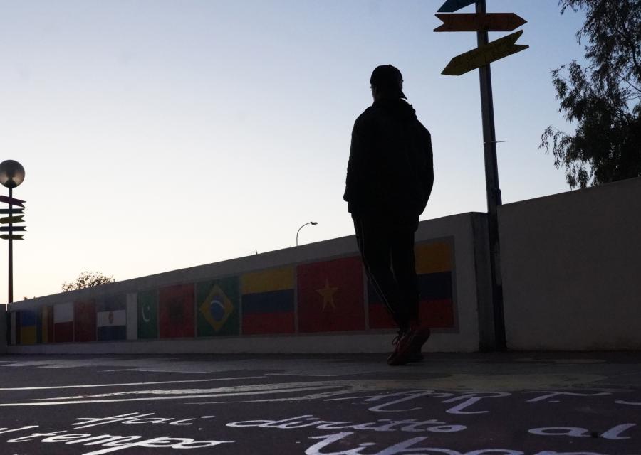Profilo in silhouette di ragazzo di spalle su pavimento con scritte