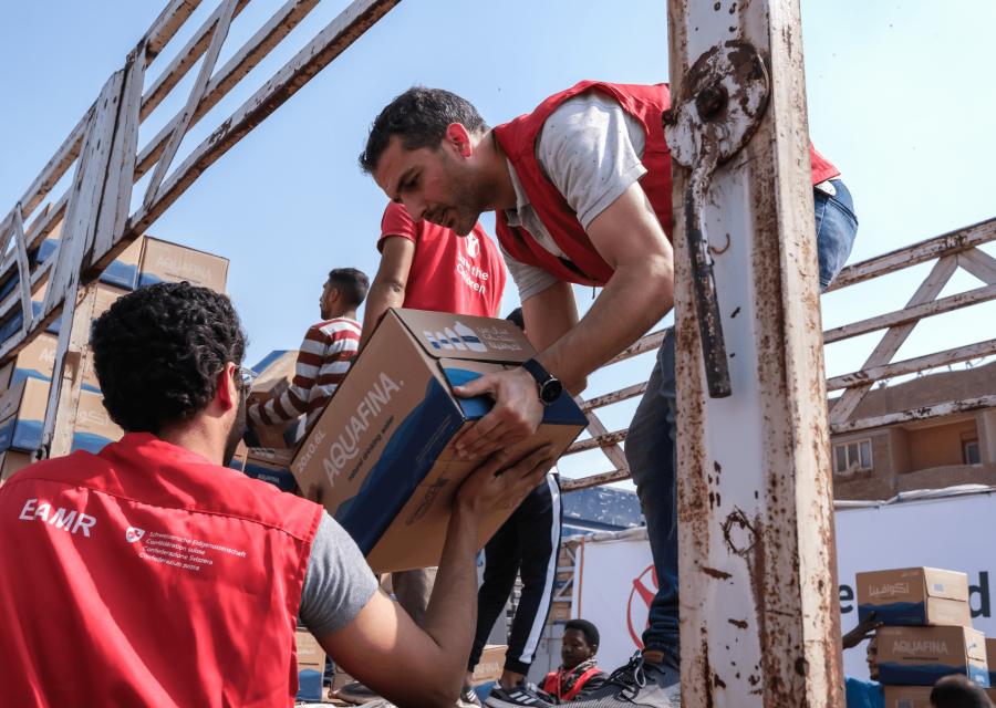 Operatore umanitario su un camion di aiuti a Gaza mentre scarica un pacco ad un collega