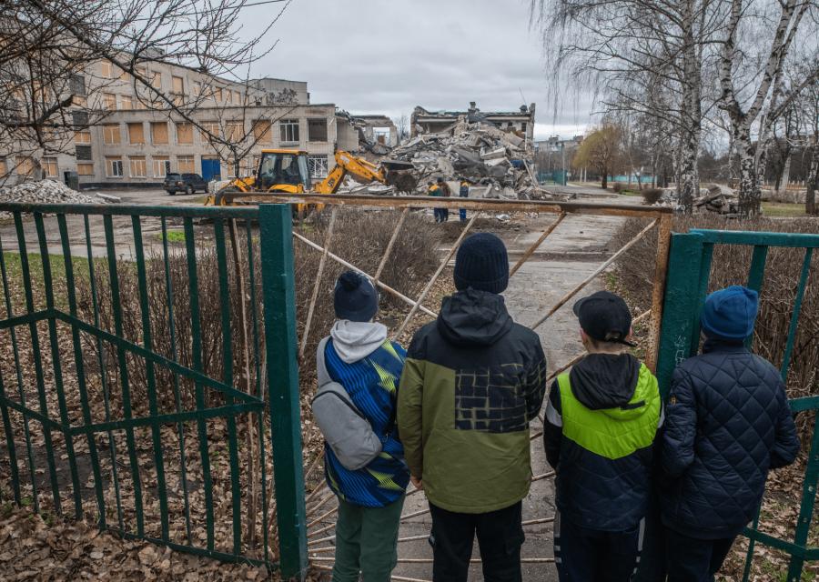 Bambini che guardano una scuola distrutta dalla guerra in Ucraina