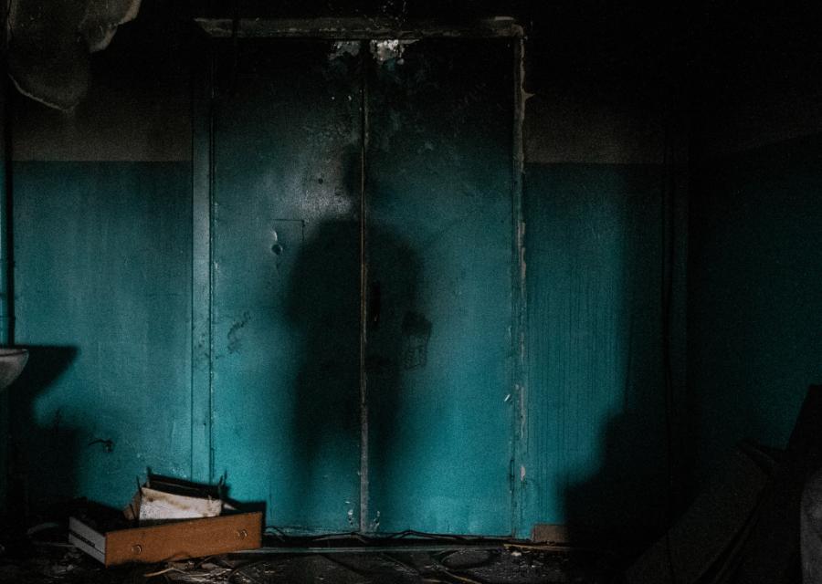 Ombra di un ragazzo in una stanza buia distrutta.