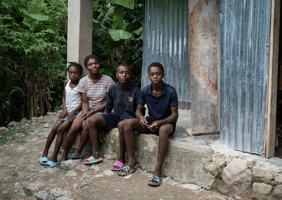 Famiglia di quattro persone sedute davanti alla loro casa ad Haiti