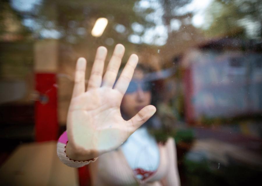 Mano  su vetro di una ragazza in segno di STOP 