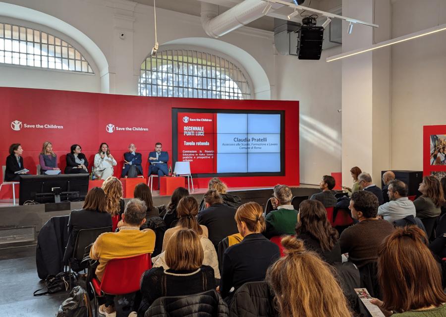 L’evento per il decennale dei Punti Luce con persone sul palco che parlano di fronte a platea di invitati