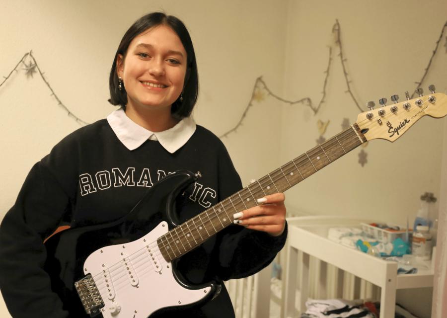 Ragazzina sorridente con in mano una chitarra 