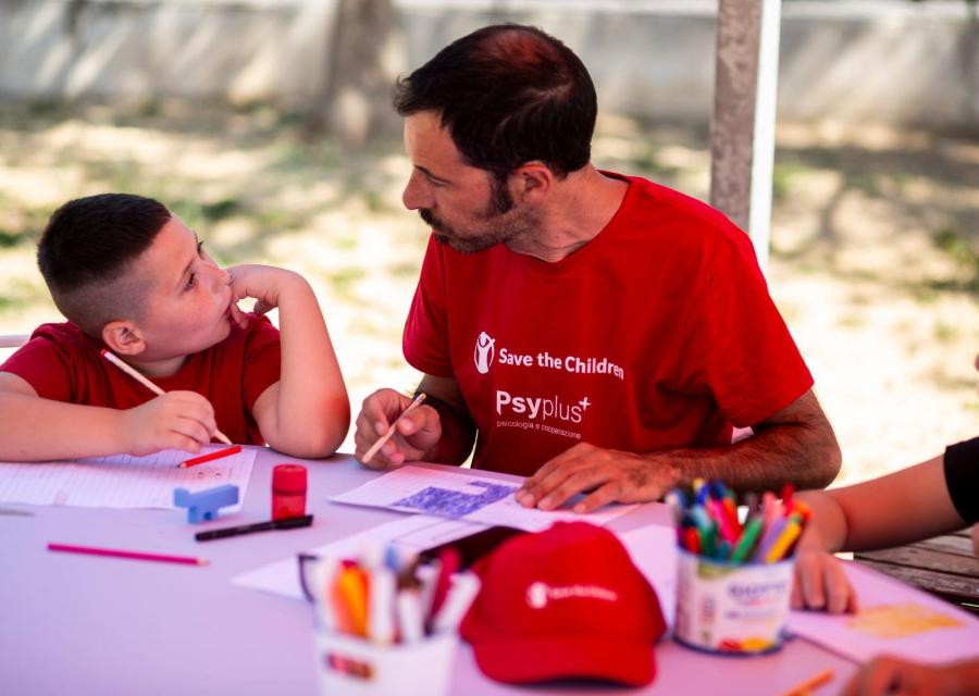 bambino parla con operatore Save the Children mentre disegnano