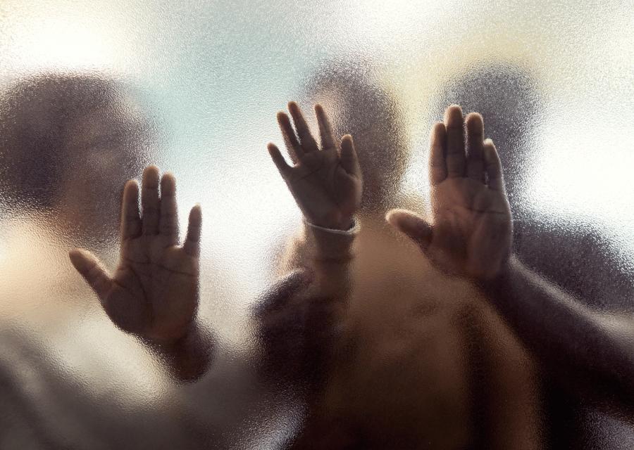 3 mani contro un vetro sfocato.