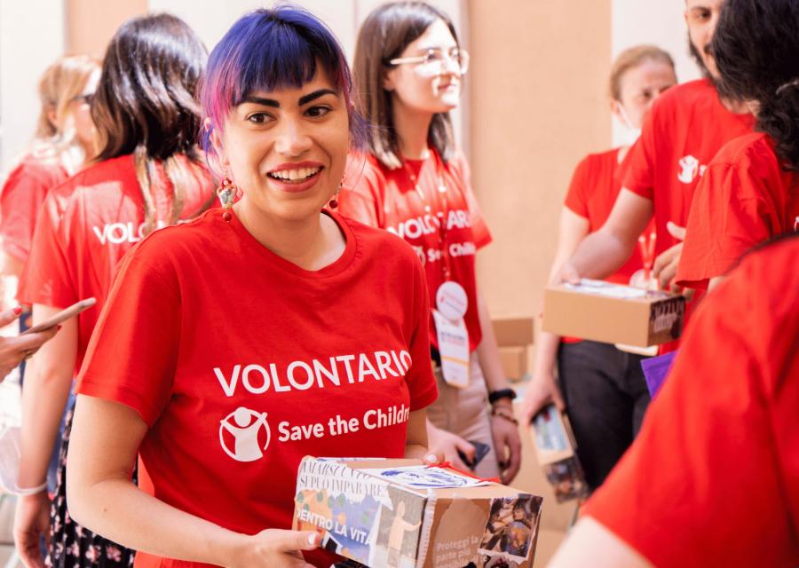Volontaria Save the Children con pacchetto in mano 