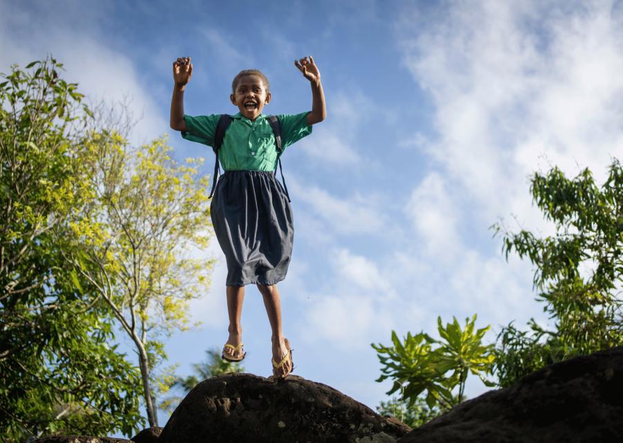 Bambina che salta da una roccia con il sorriso