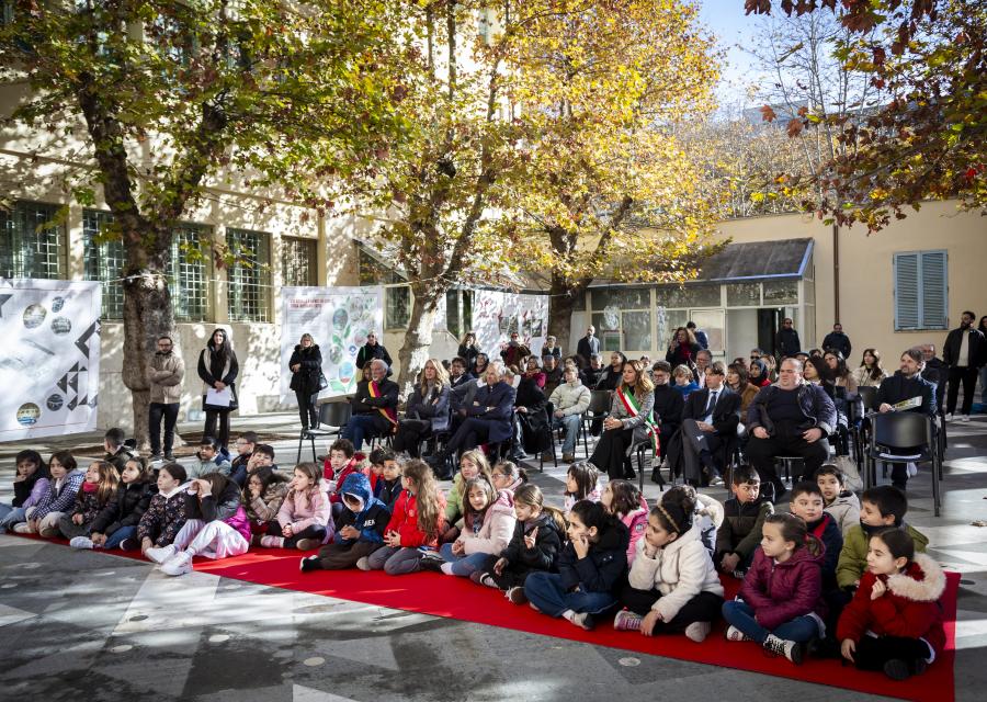 gruppo bambini seduto a terra nel cortile di una scuola
