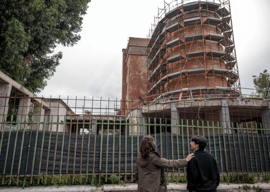 Due ragazze di fronte a una ringhiera e un palazzo in ricostruzione 