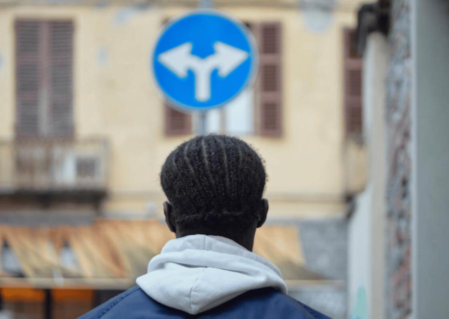 Ragazzo di spalle di fronte ad un cartello stradale