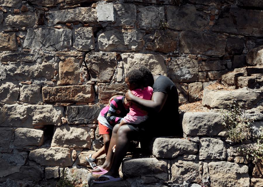 Mamma con figli con volto coperto che si abbracciano sulle scale