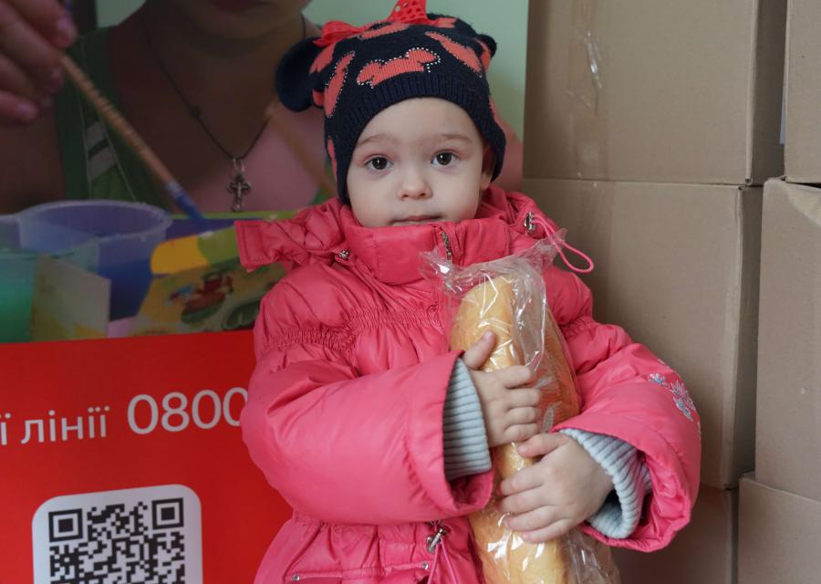 bambina con cappotto rosa mangia pane 