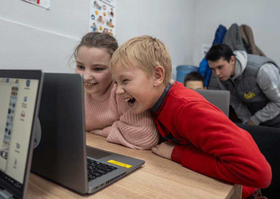 Due bambini di fronte ad un computer che ridono 
