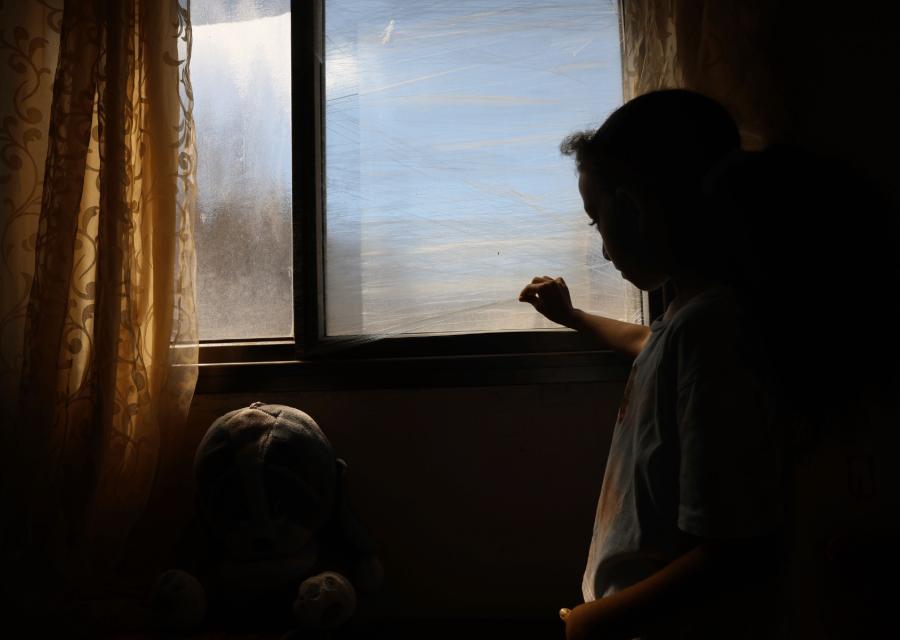 Bambina che attacca un pezzo di muro sulla finestra rotta.