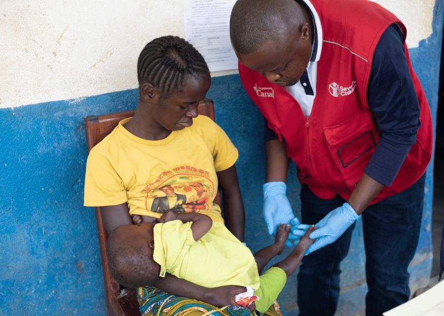 Operatore Save the Children in RDC che visita bambina malnutrita
