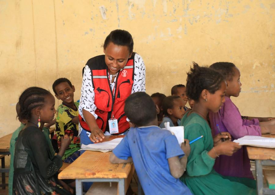operatrice Save the Children parla a bambini tra i banchi di scuola