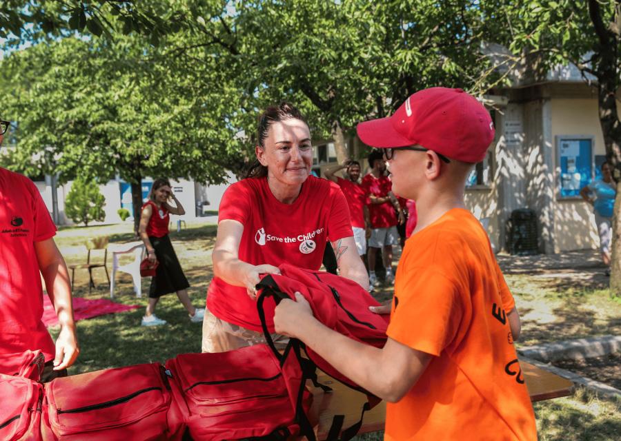 Volontaria Save the Children durante un emergenza che distribuisce ad un bambino uno zianetto