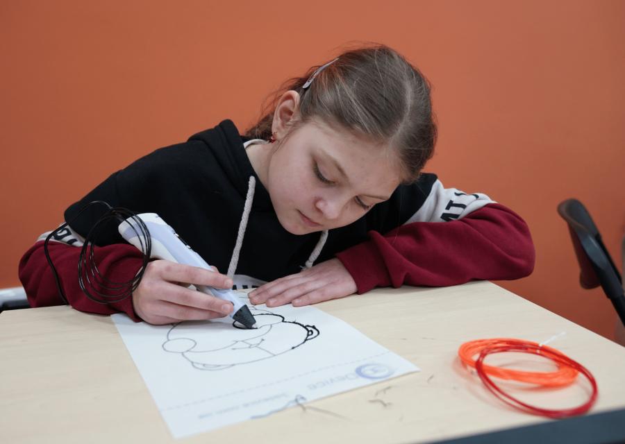 Bambina che disegna su un foglio con penna tecnologica
