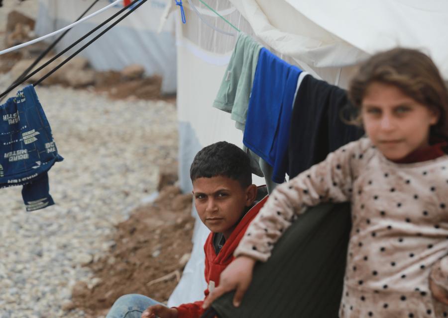 Bambini siriani vicino alla loro tenda che guardano 