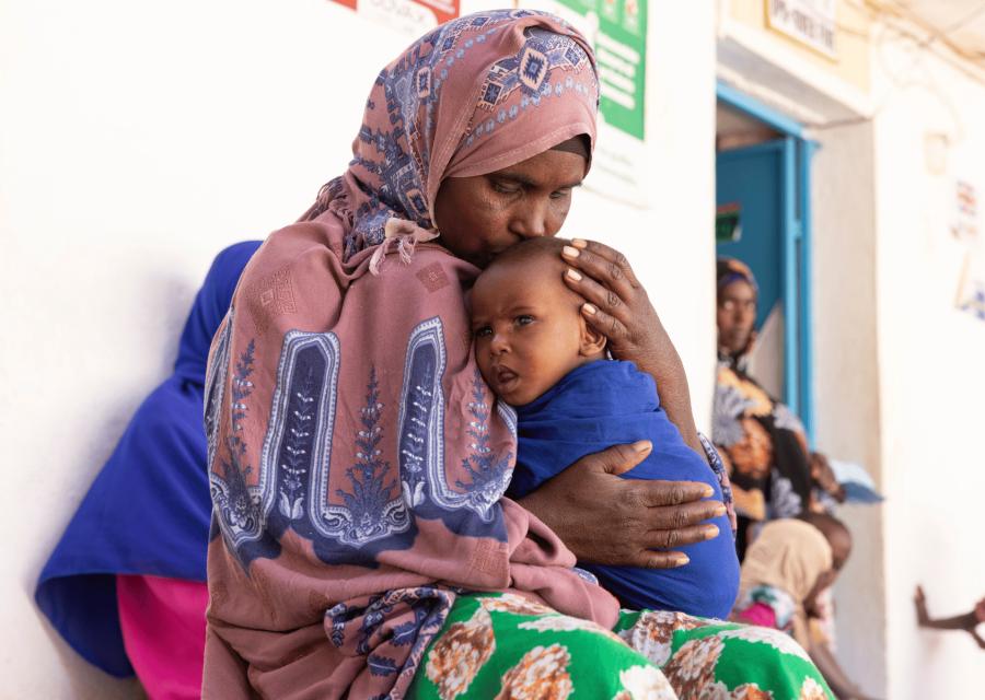 Mamma somala che abbraccia e bacia sulla fronte il figlio 