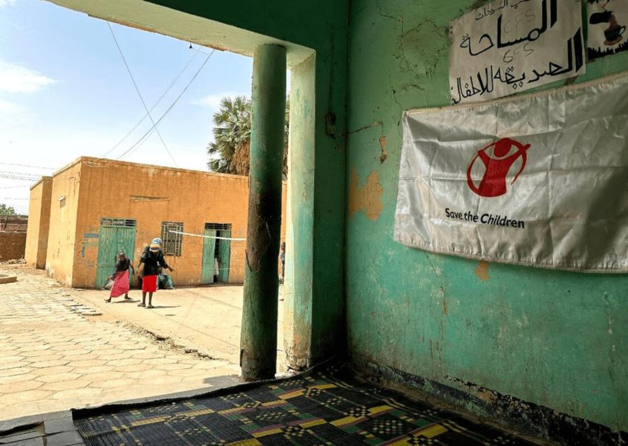 Muro di una clinica di Save the Children in Sudan e nello spiazzale alcuni bambini che corrono 