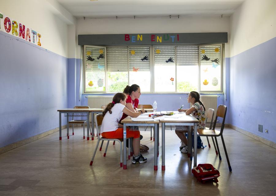 bambine disegnano intorno ad un tavolo insieme ad operatrice Save the Children